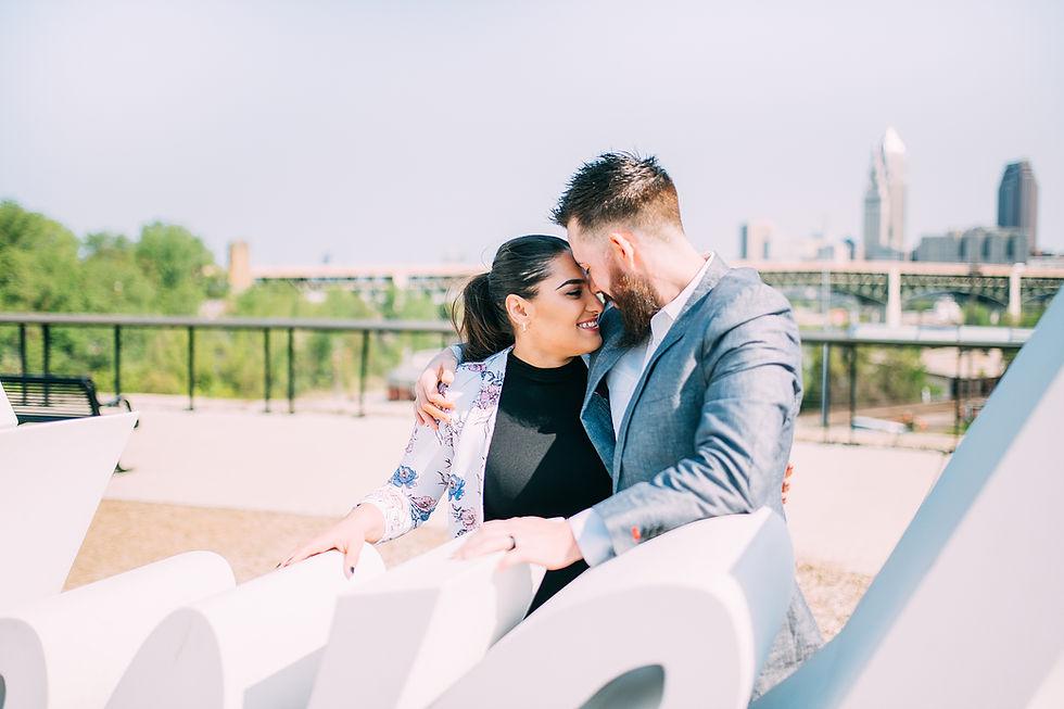 Man and woman stand close to one another with the Cleveland skyline in the background