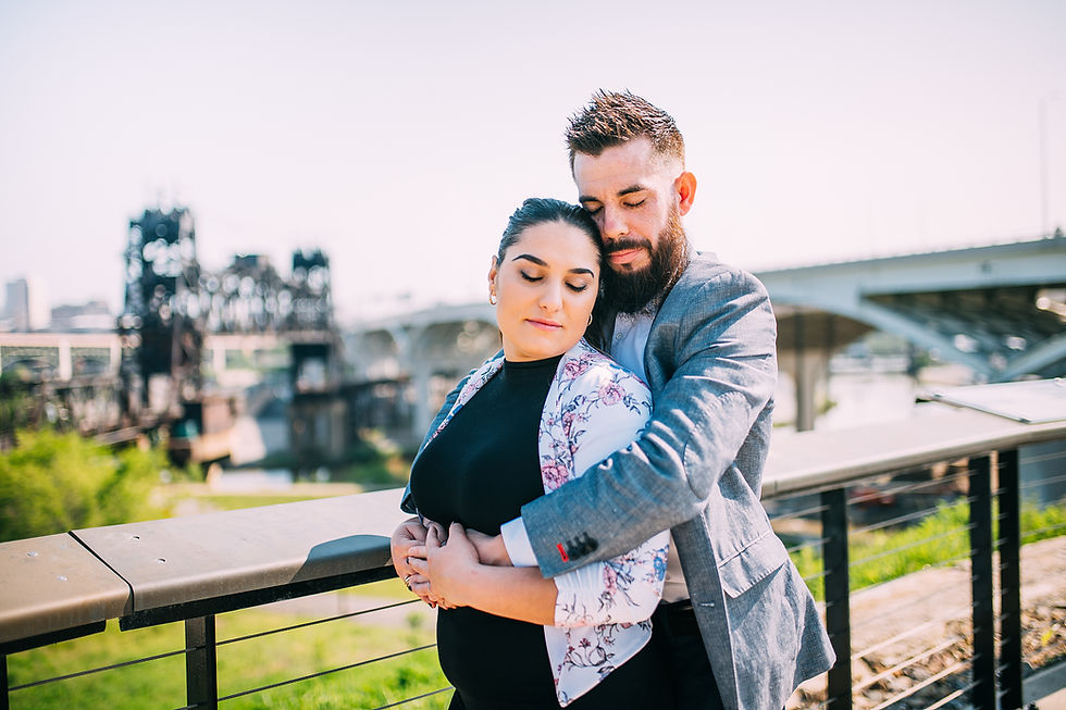 Man and woman snuggle together with their eyes closed with the Cleveland skyline