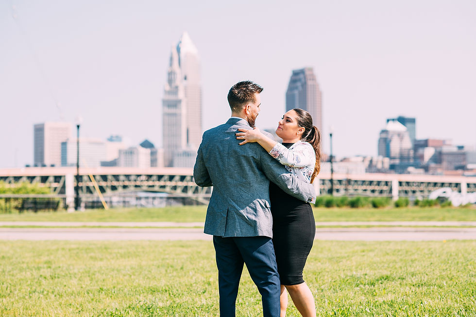 Man and woman slow dance on grass with the Cleveland skyline in the background