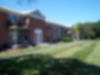 Packshot photography of a red brick apartment building facade on a sunny day. Manicured lawns and walkways lead to the entrance.