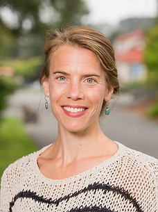 Portrait of Jennifer Marlow, a white woman with short blonde hair, smiling, wearing a white sweater with black stripes