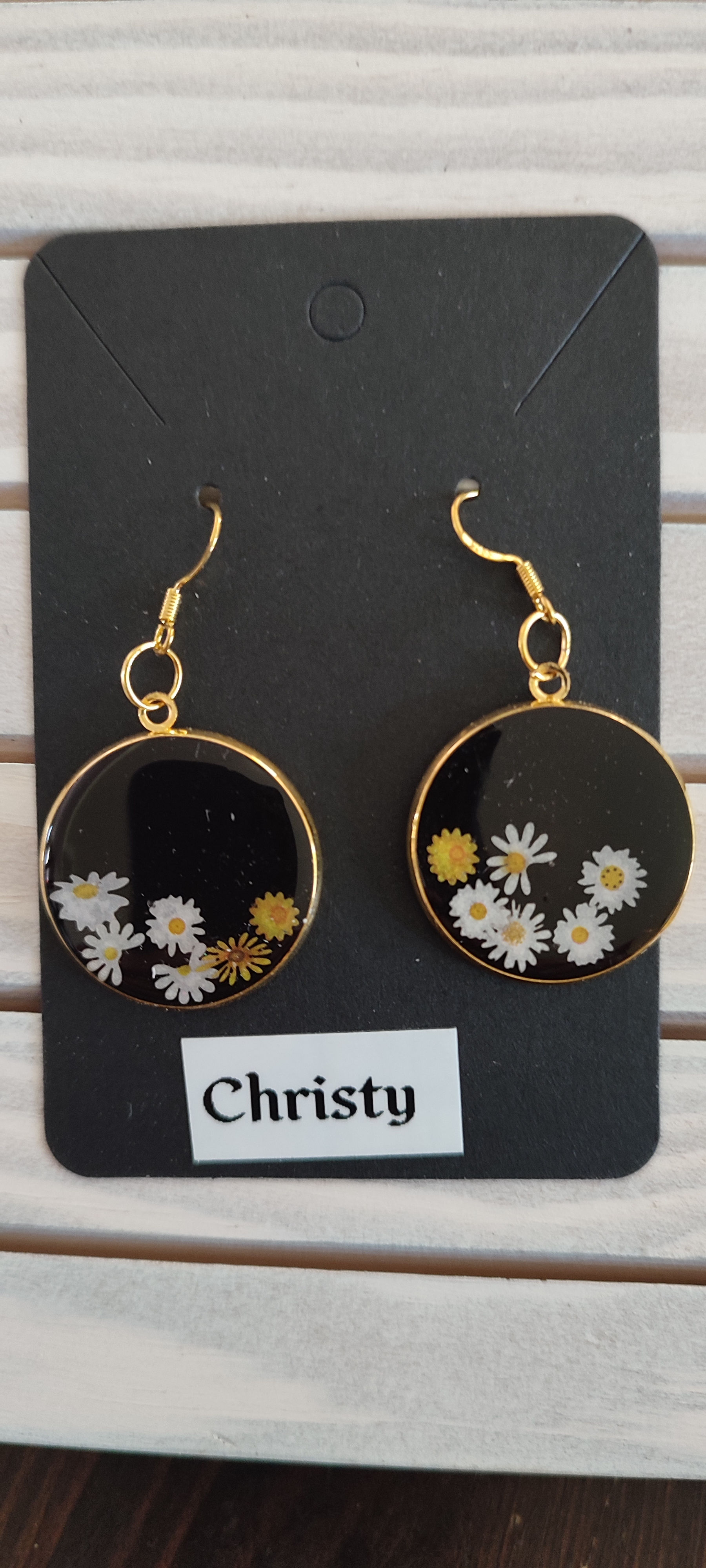Boucles d'oreilles rondes dorées avec des marguerites et le nom Christy.