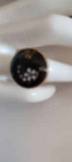 Bague noire ornée de fleurs blanches, portée sur une main, PAMOISON élégance.