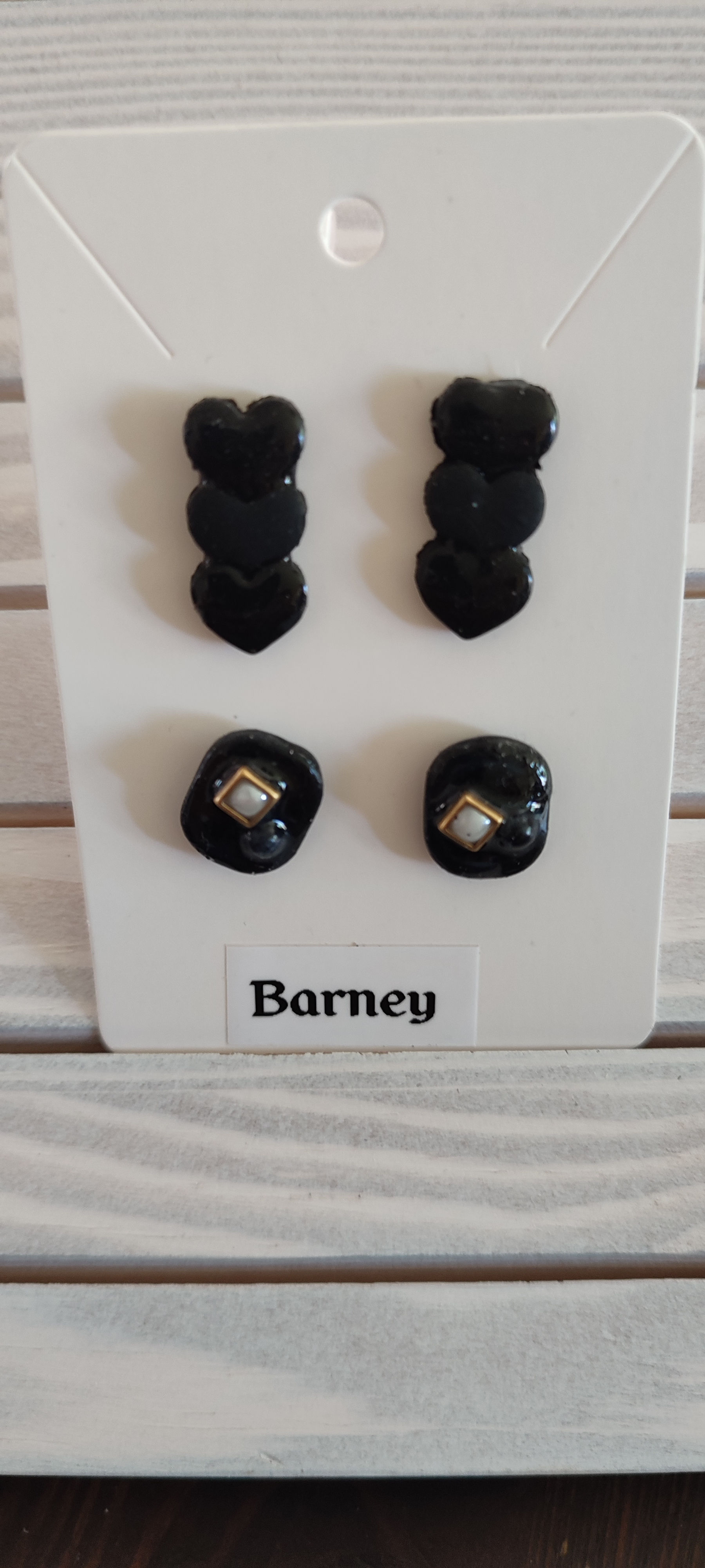 Boucles d'oreilles noires Barney coeur et carrées, fond blanc, détails dorés. cinebycine