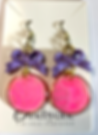 Boucles d'oreilles rose avec nœuds violets, texte cinebycine sur fond blanc, brillantes.