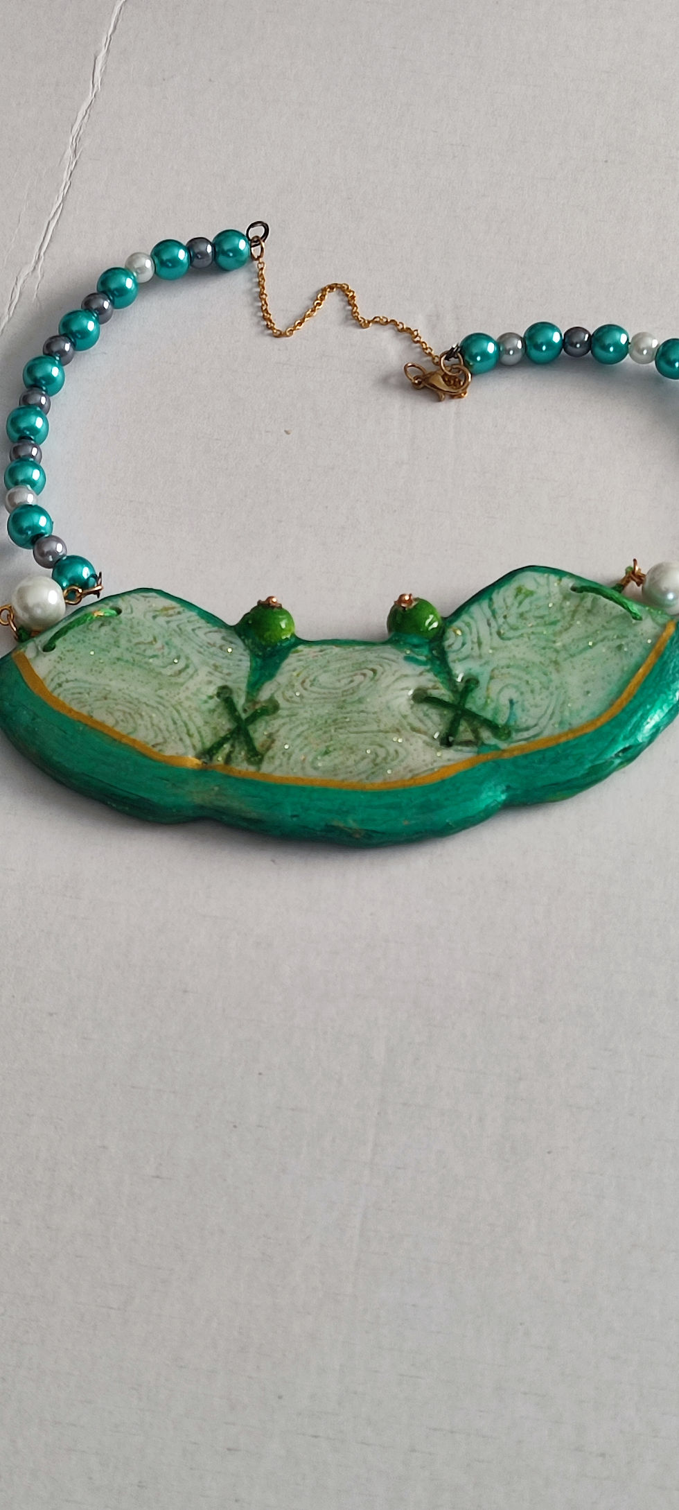 Collier fantaisie vert avec perles blanches et vertes sur fond blanc cinebycine