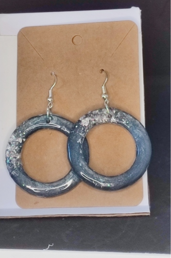 Miniature : Boucles d'oreilles circulaires bleues avec du glitter argenté, sur fond marron.