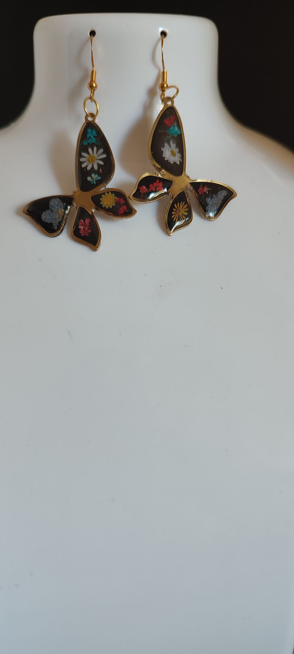 Boucles d'oreilles dorées avec des motifs floraux multicolores sur fond blanc.