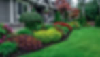 A picturesque and colorful front yard featuring a meticulously maintained garden bed fille