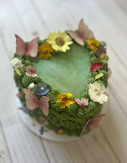 Green heart cake with edible flowers and pink butterflies