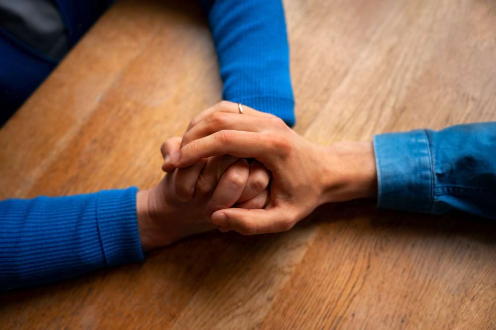 A person holding the hands of another person to show compassion.