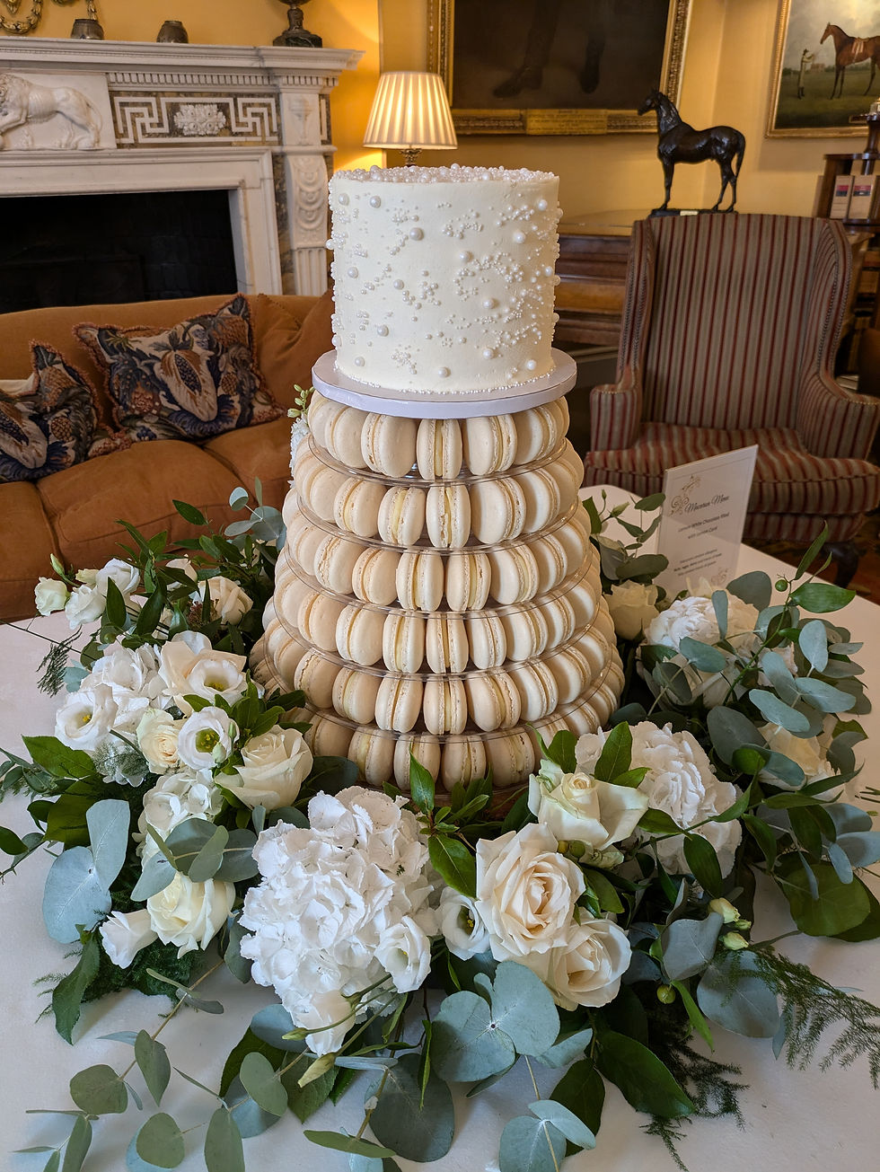 Wedding ivory macaron tower with Victoria sponge wedding cake sitting on the top of the tower.