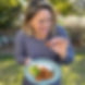 Emmylou holding a plate of chicken cashew stir fry with fresh basil and a sweet-savoury chilli sauce.