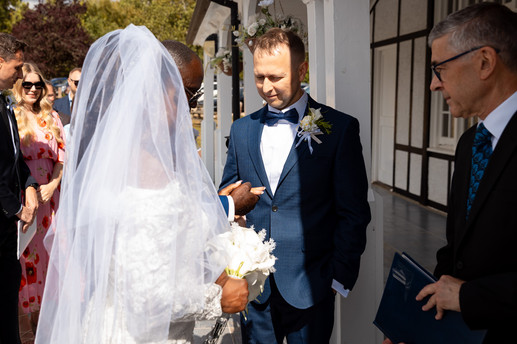 Bride approaching groom during outdoor ceremony at London Shenley Club