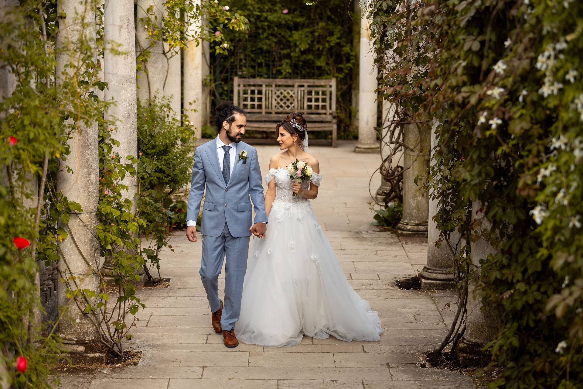 Bride and groom walking through garden after ceremony in Hertfordshire
