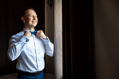 Groom getting ready by the window at London Shenley Club wedding in Hertfordshire
