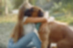 An young girl hugging a Boxer dog that she is fostering and caring for.