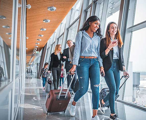 Travelers walking through an airport terminal with luggage, representing professionally managed airport and group transport