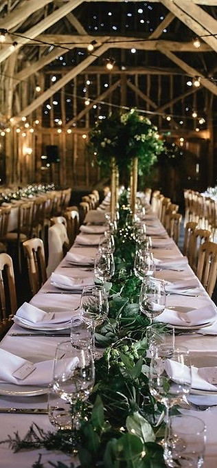 Interior of The Barn at Edworth Manor set up for a wedding with long banqueting tables stretching into the distance
