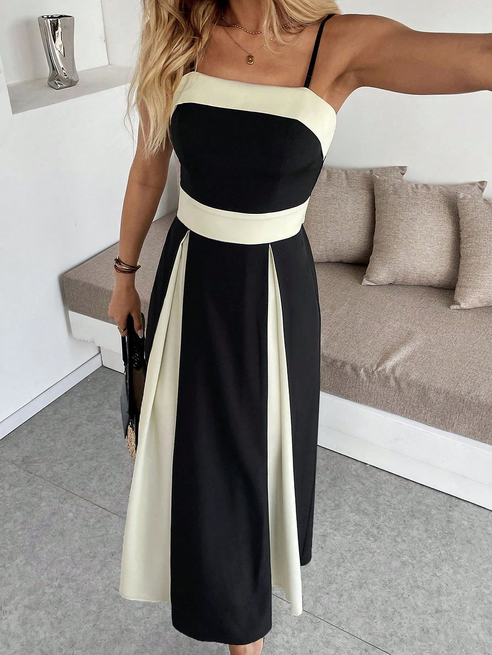 Black and white long dress with patchwork details, thin straps, and a waist bow, worn by a woman indoors, paired with black sandals and a straw bag