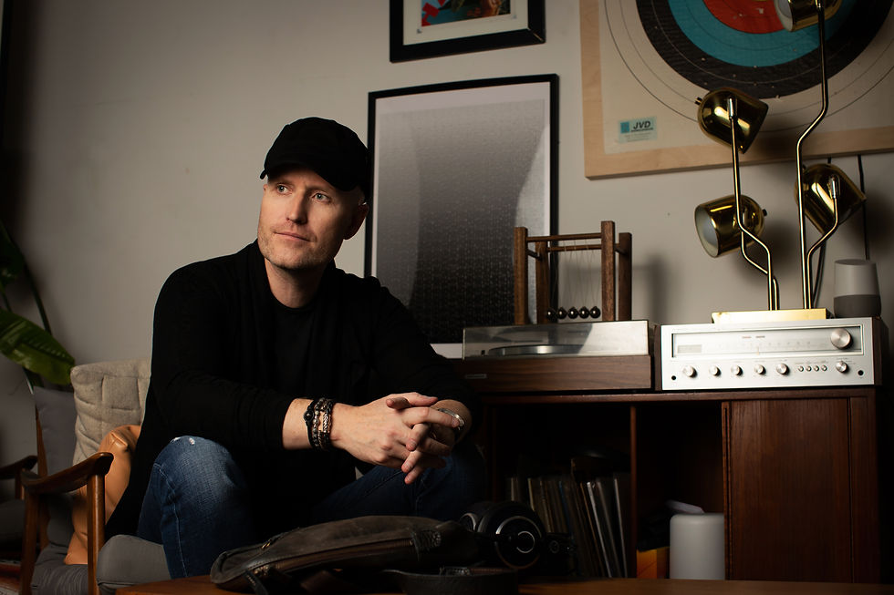 composer Andrew Lockington sitting in a chair beside a turntable console