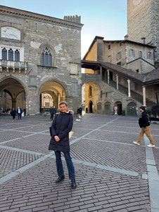 Astrid Dröse steht auf einem offenen Platz in Bergamo. Hinter ihr sind alte Gebäude zu sehen.