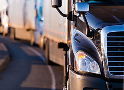 Details of dark semi truck on the road on blured truck and trailer background.jpg