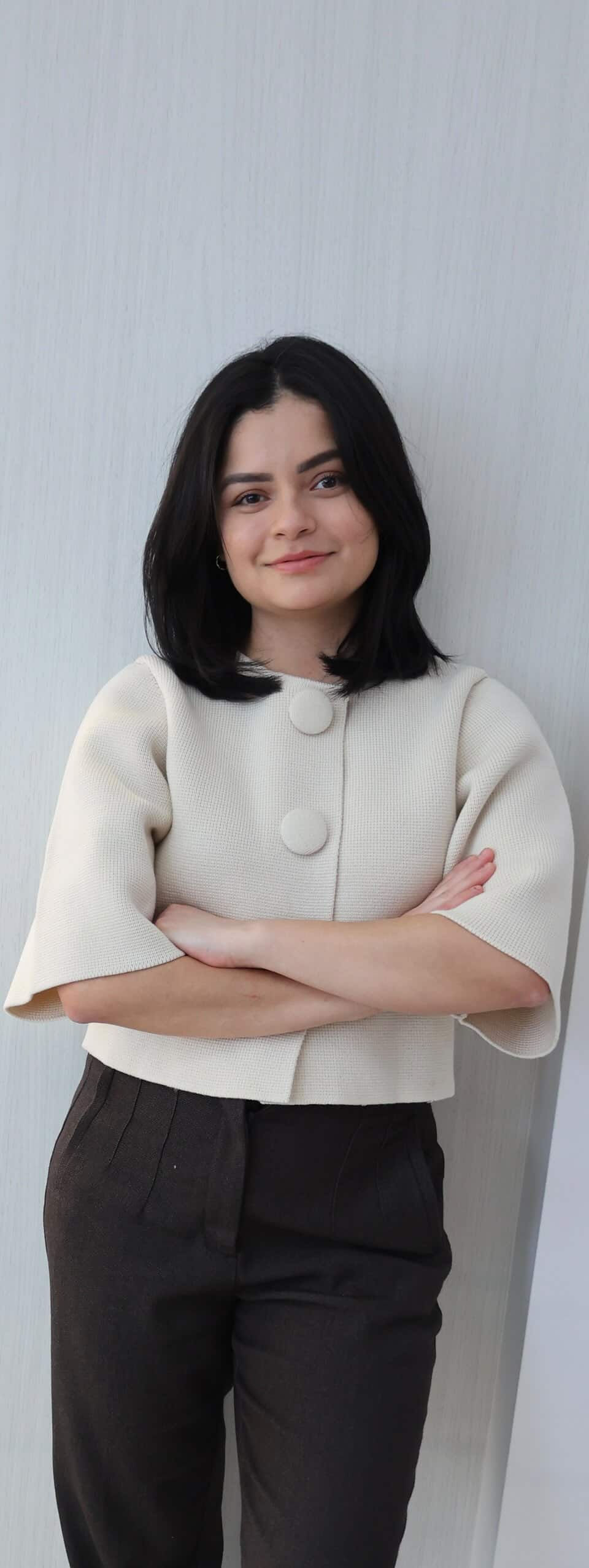 Jeune femme souriante aux bras croisés.