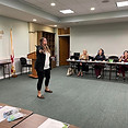 Jennica Hunter speaking at Chamber of Commerce with wireless mic to audience wearing headphones.