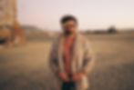 Handsome man standing in the desert with a furry jacket