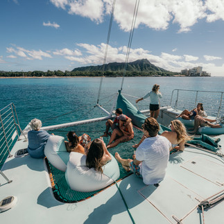 a family lounging on the nets of a catamaran in honolulu, hawaii