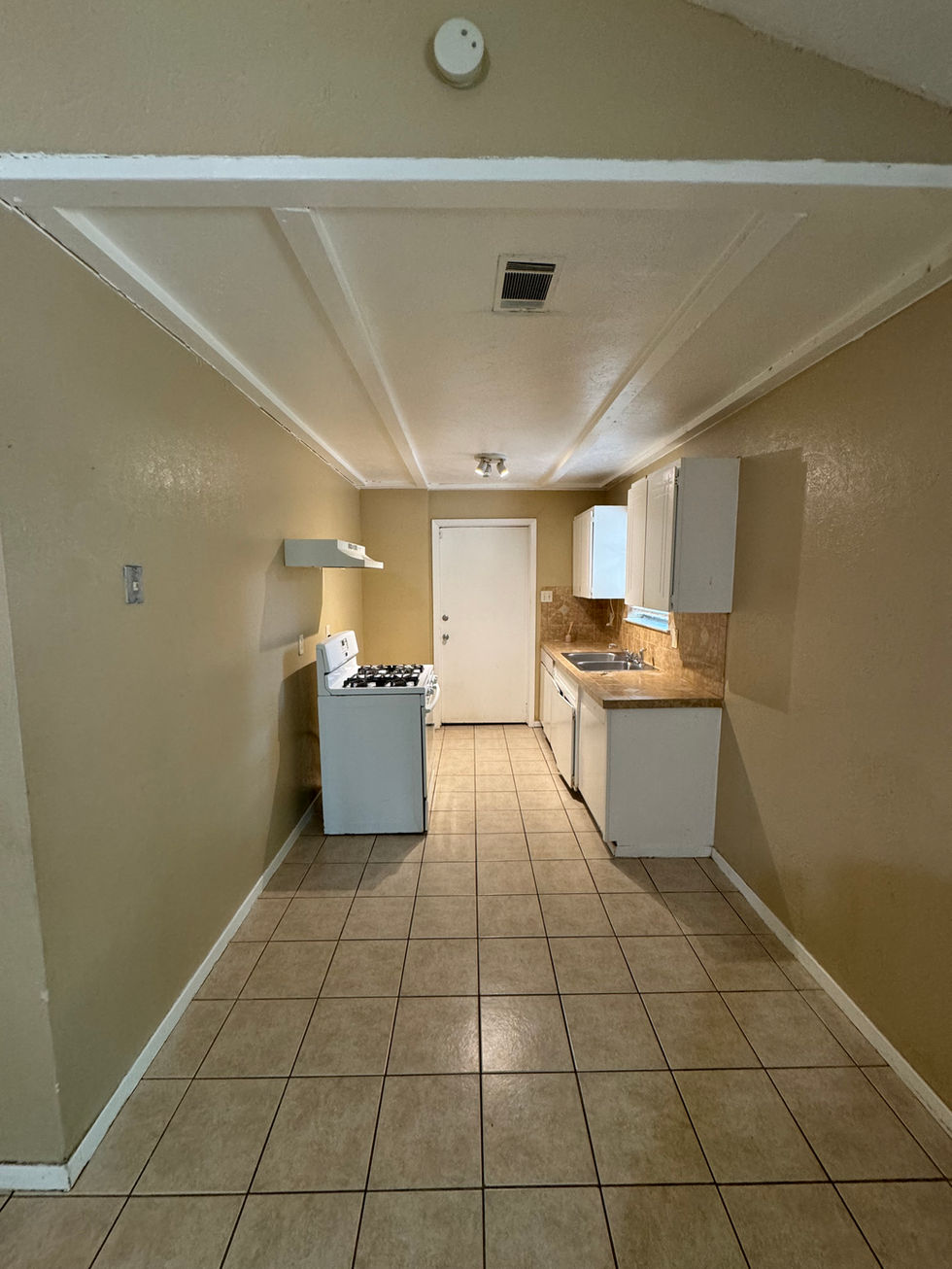 an empty kitchen with a white stove and white cabinets