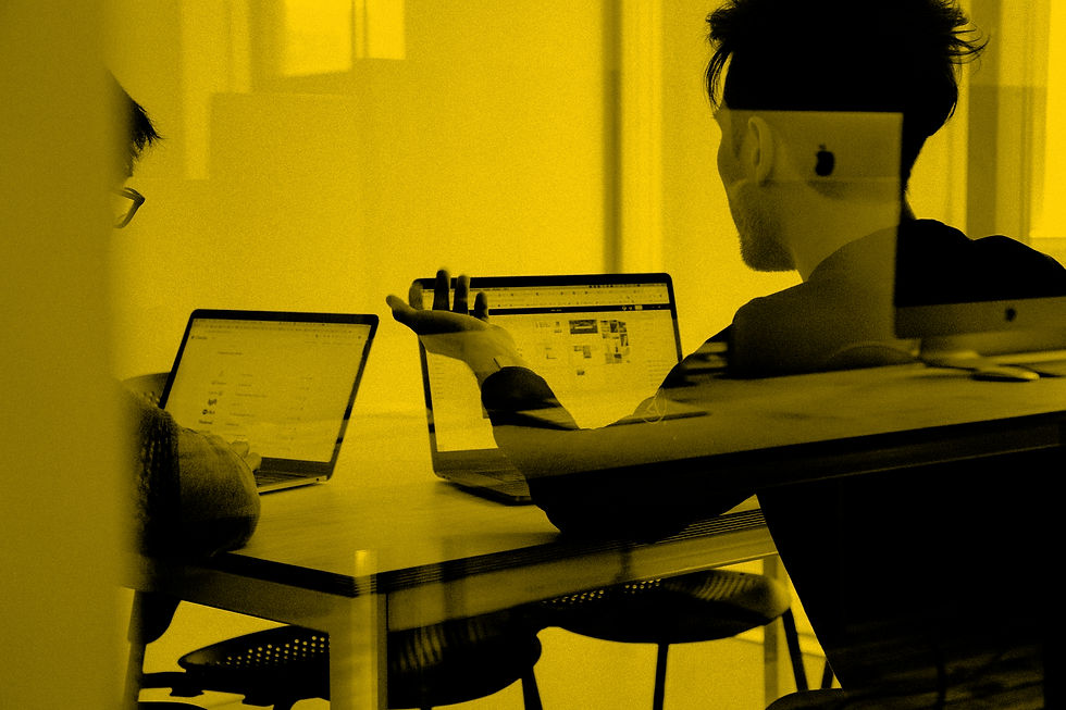 Two people working on laptops in an office meeting.