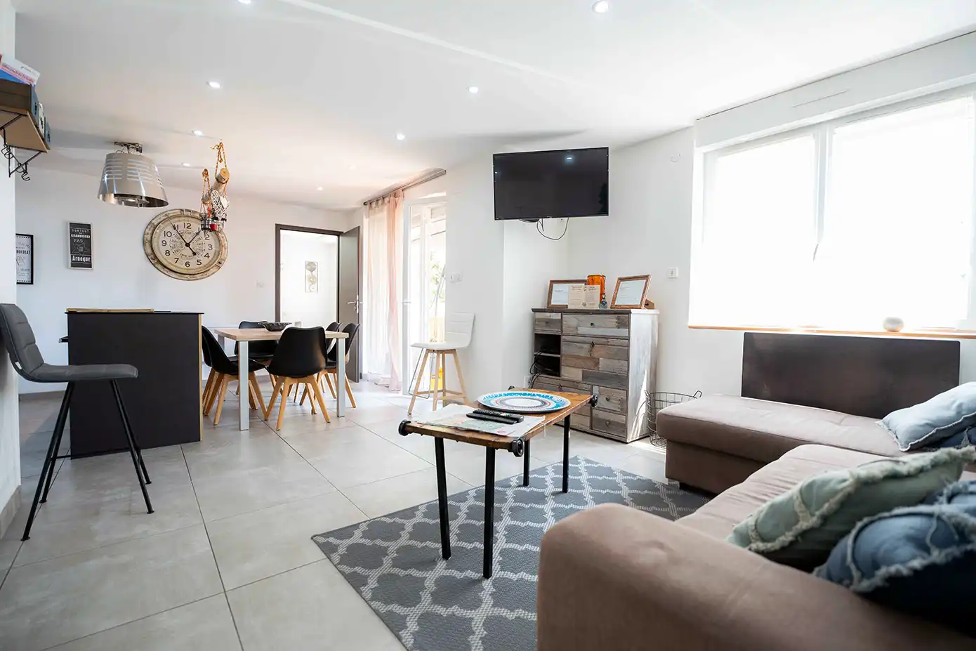 Photo immobilière montrant l'intérieur d'un appartement lumineux avec un canapé et une cuisine