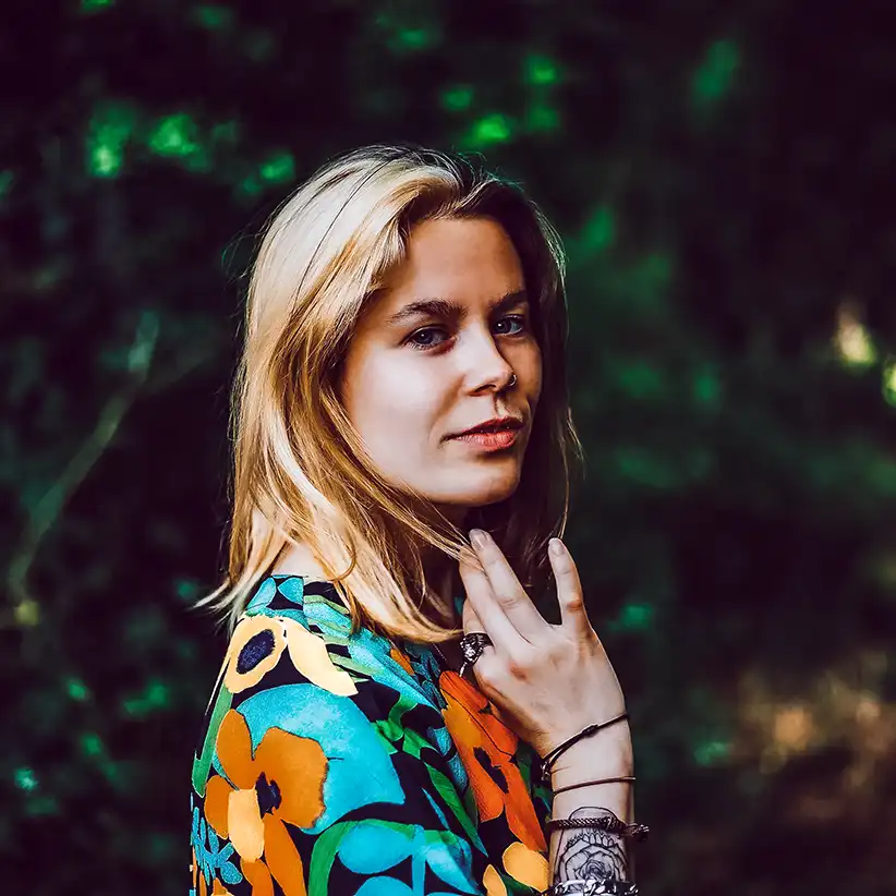 Portrait d'une femme aux cheveux blonds regardant l'objectif. Elle porte une robe à fleur