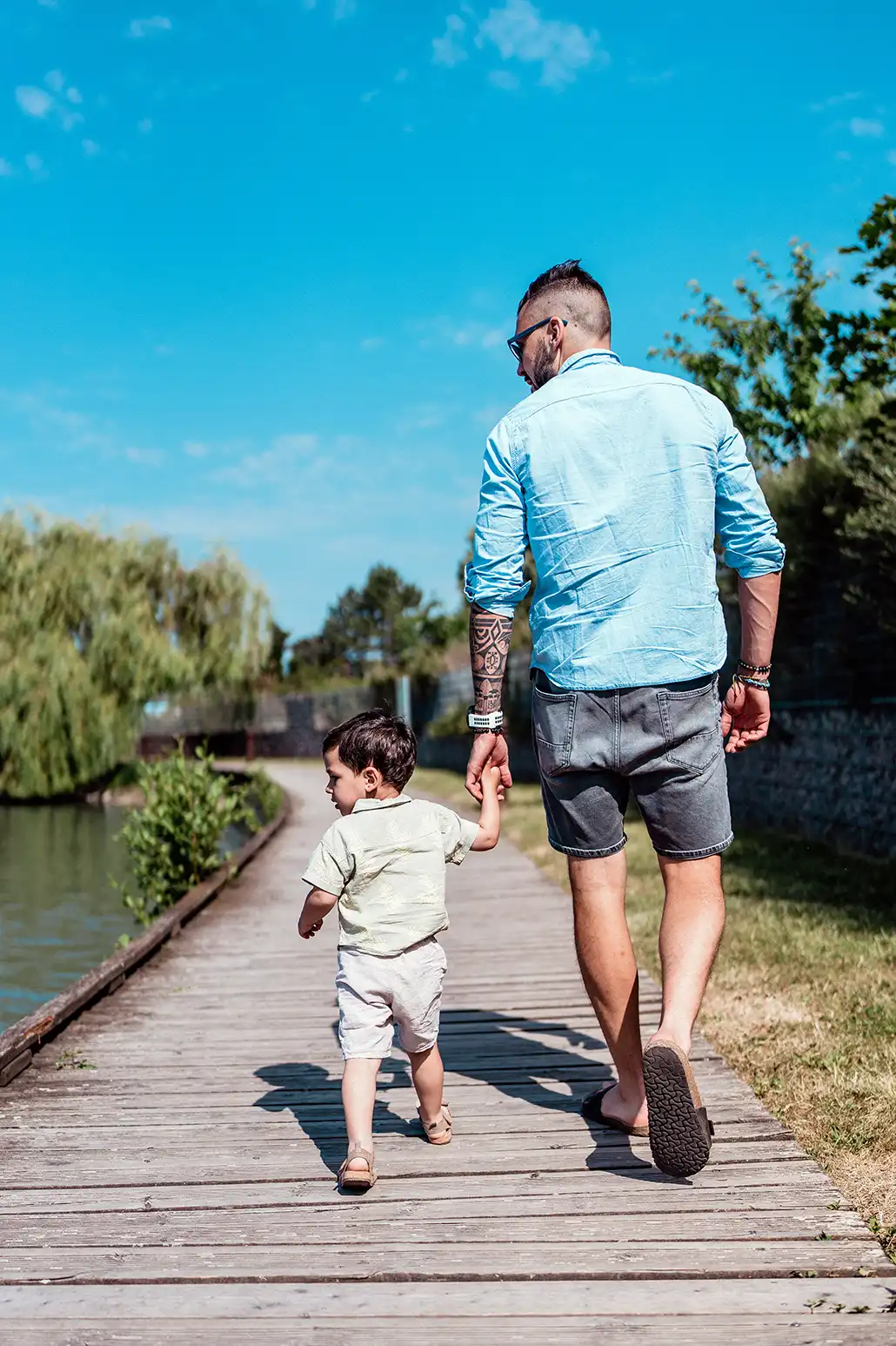 Photo de famille montrant un père marchant avec son fils main dans la main de dos