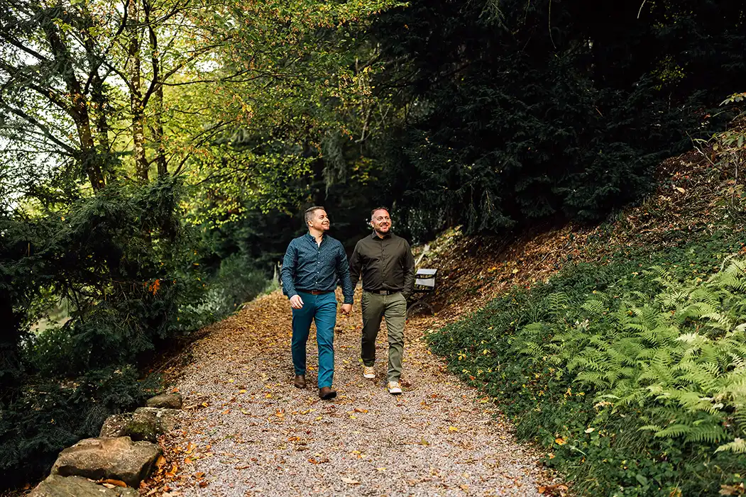Un couple de deux hommes marchant dans la forêt. Ils se tiennent la main et sourient