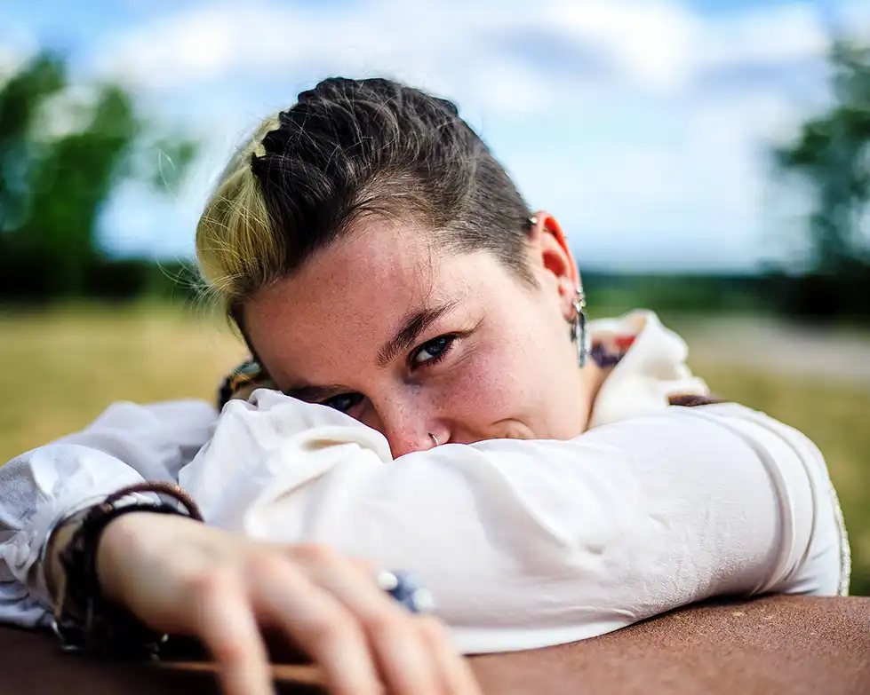 Portrait d'une femme affalé sur un caillou. On ne voit qu'un seul oeil
