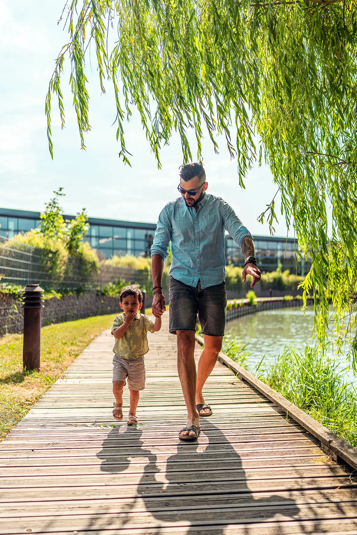 Photo de famille montrant un père marchant avec son fils main dans la main de face