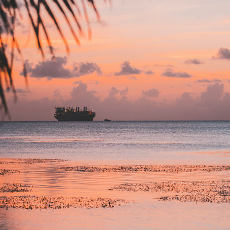 Caribbean beach at night with a ship in the distance.