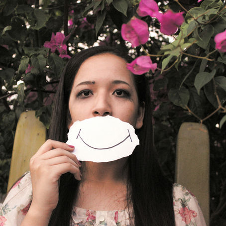 Sad woman with a drawing of a smile against her lips