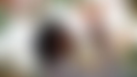 Black woman reaches up to touch flowers on a tree