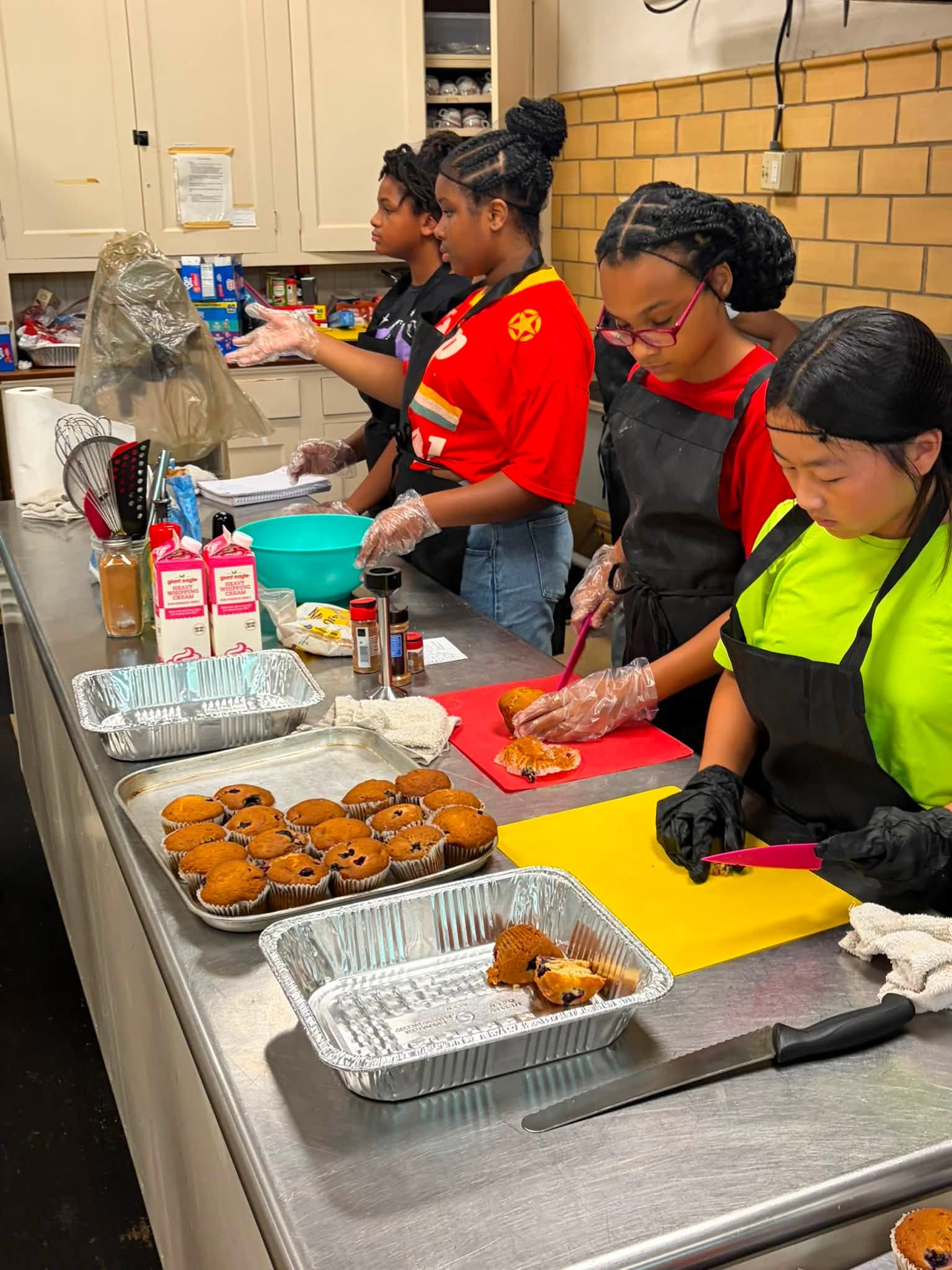 Youth working together in a kitchen setting during the culinary workshop.