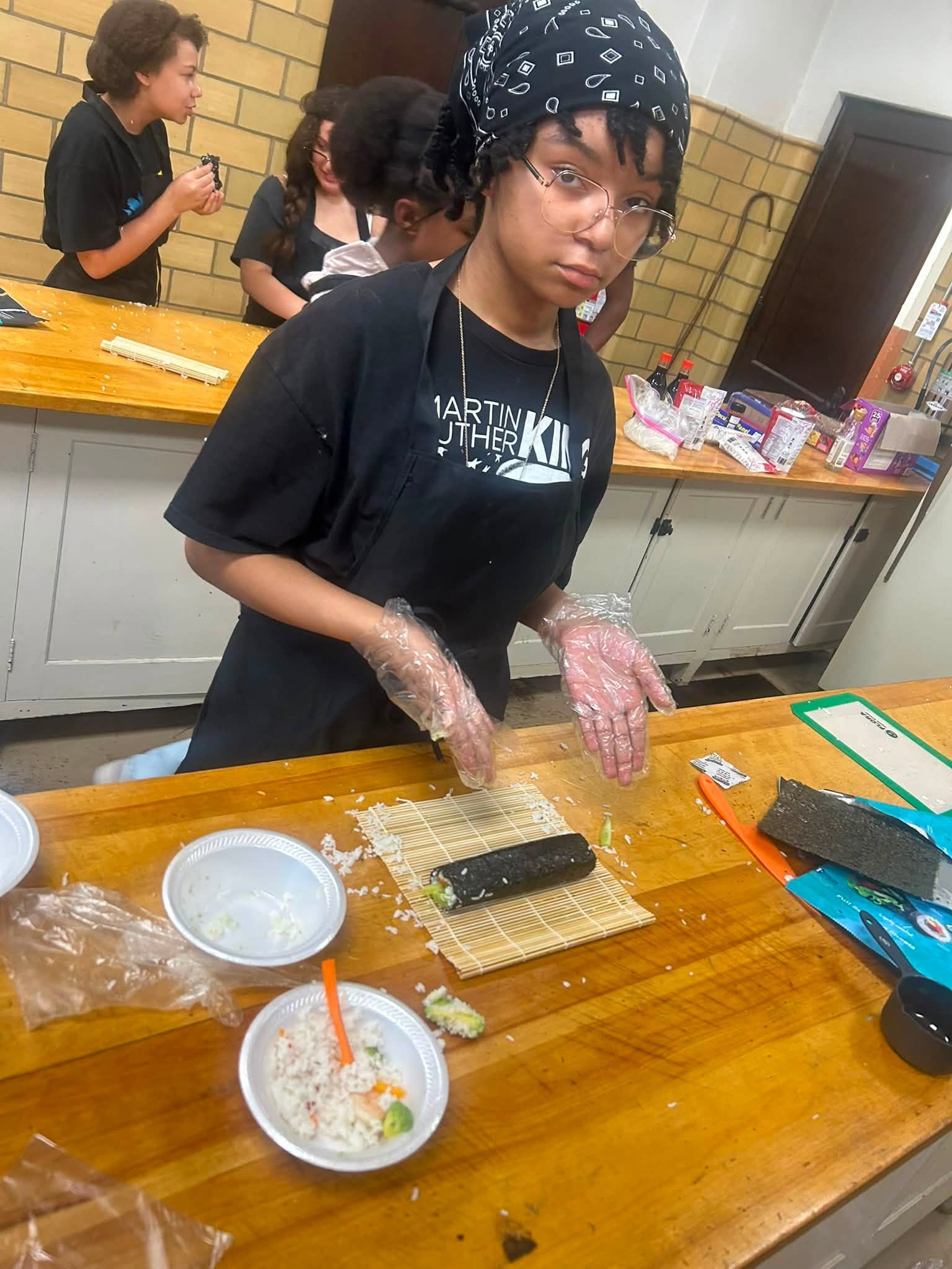 Youth working together in a kitchen setting during the culinary workshop.