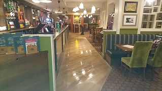Clean interior of a pub with a bar on the left and booth seating on the right