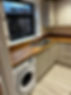featuring a washing machine, with indistinct appliances and surfaces in the background