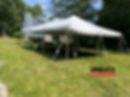 a white 20x30 canopy with poles and scalloped edges secured onto a lawn