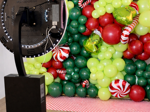 Photo booth with balloons, candy canes background, and a festive event setting.