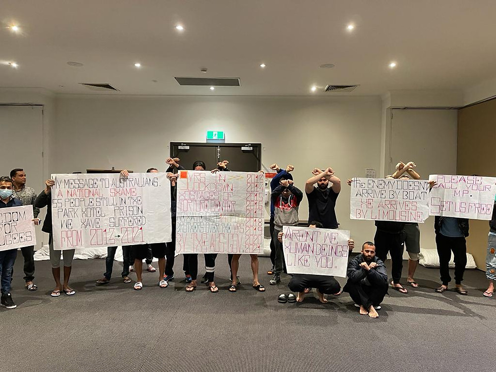 refugees holding signs in protest to be released from detention