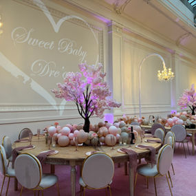 Elegant pink event space with 'Sweet Baby Dre's' projection and cherry blossoms.